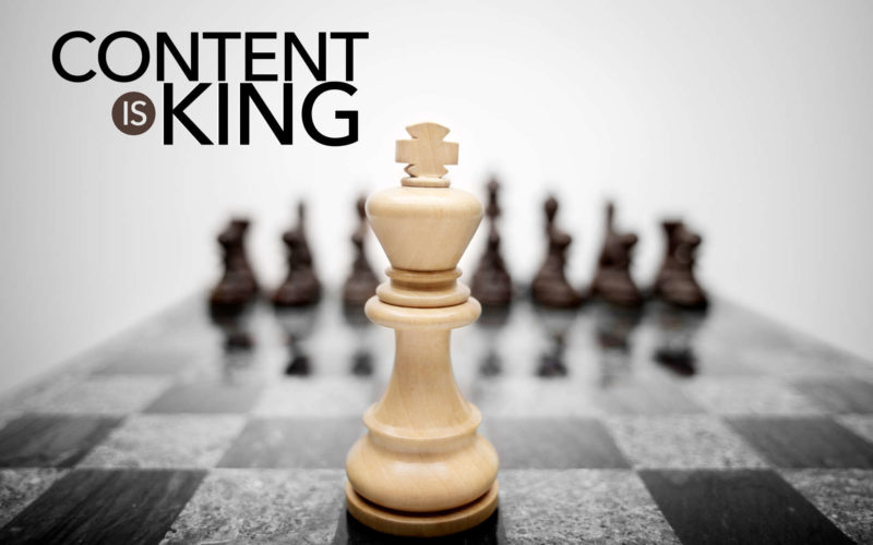 konten adalah gambar raja catur berwarna putih di atas papan catur dengan tulisan content is king